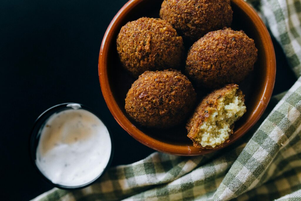 Close-up shot of crispy falafel balls served with creamy tahini sauce in an inviting setting.